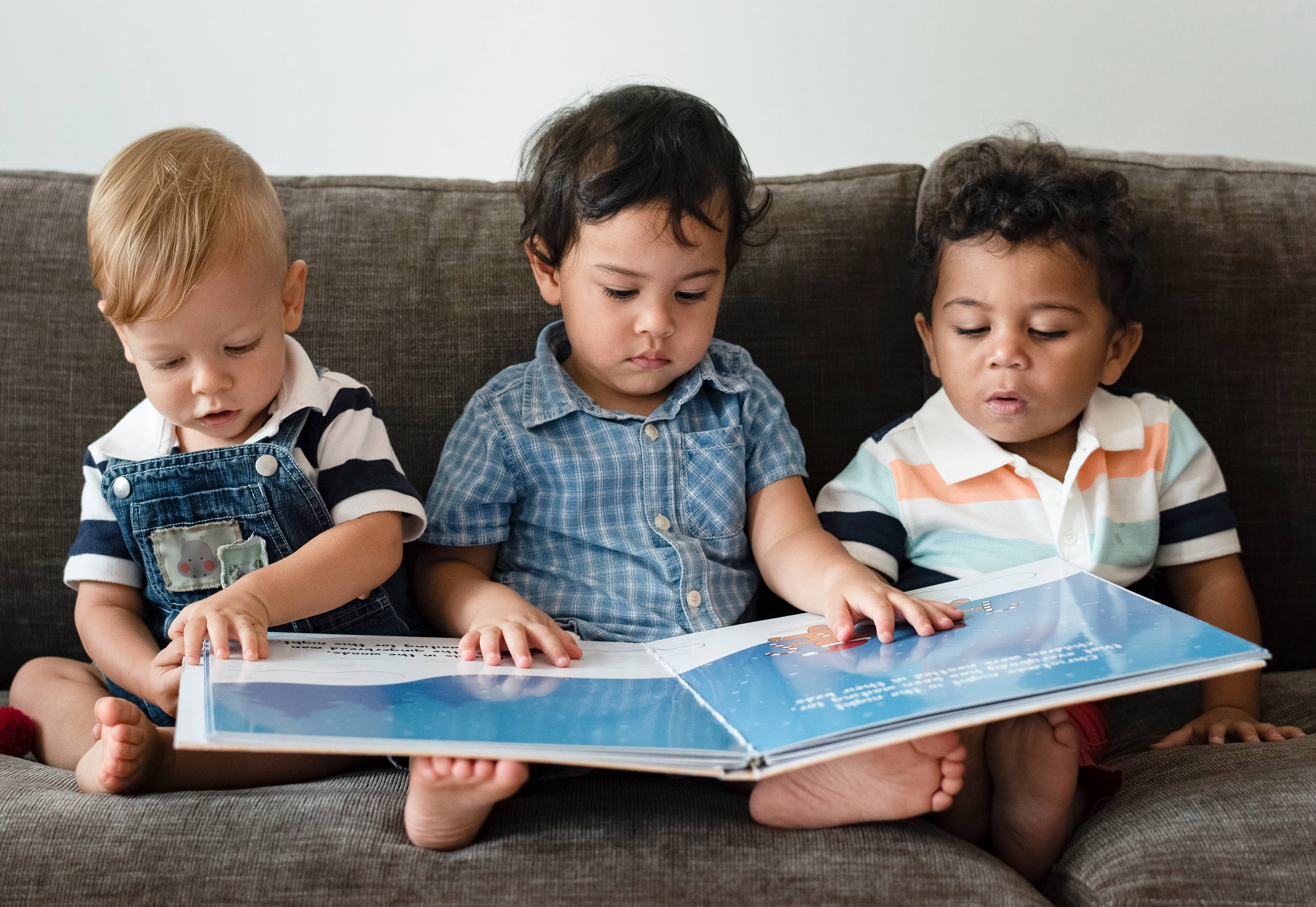 threelittleboysreadingabookonasofa