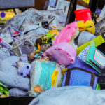 Piles of toys and school supplies belonging to a 1 and 5-year-old left out in the sun as the family goes through and washes all of their belongings.