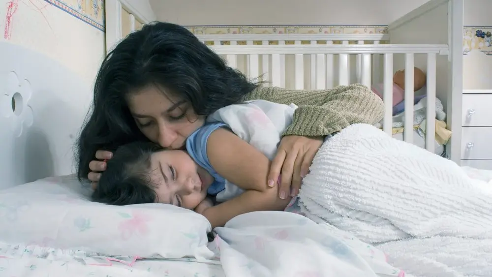 mothersayinggoodnightandtuckingherdaughterintobed