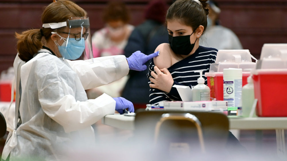 Nurse injecting a woman with COVID-19 vaccine