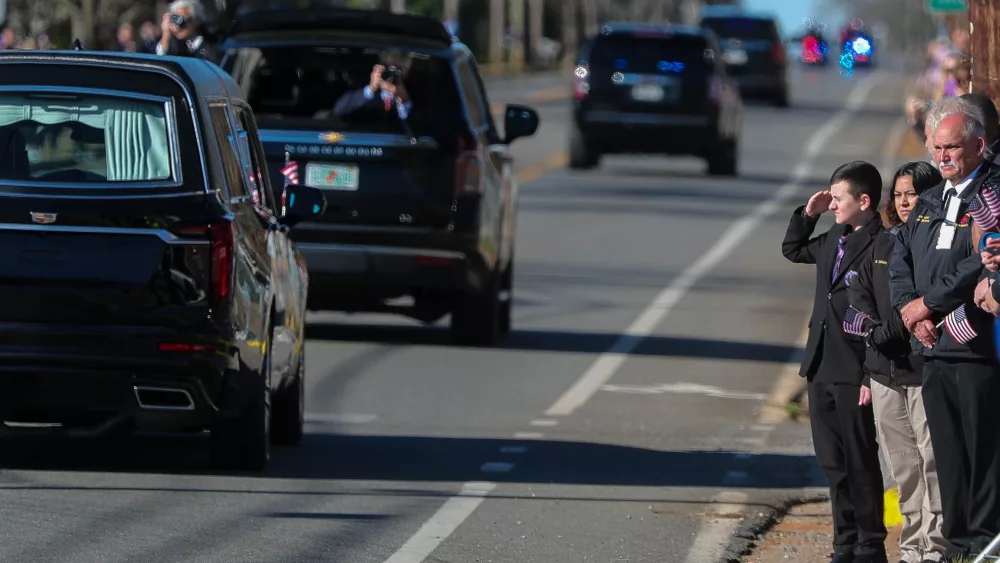 A boy in a formal suit salutes as the hearse carrying former President Jimmy Carter travels along the through Plains, Georgia on Saturday, Jan. 4, 2025.