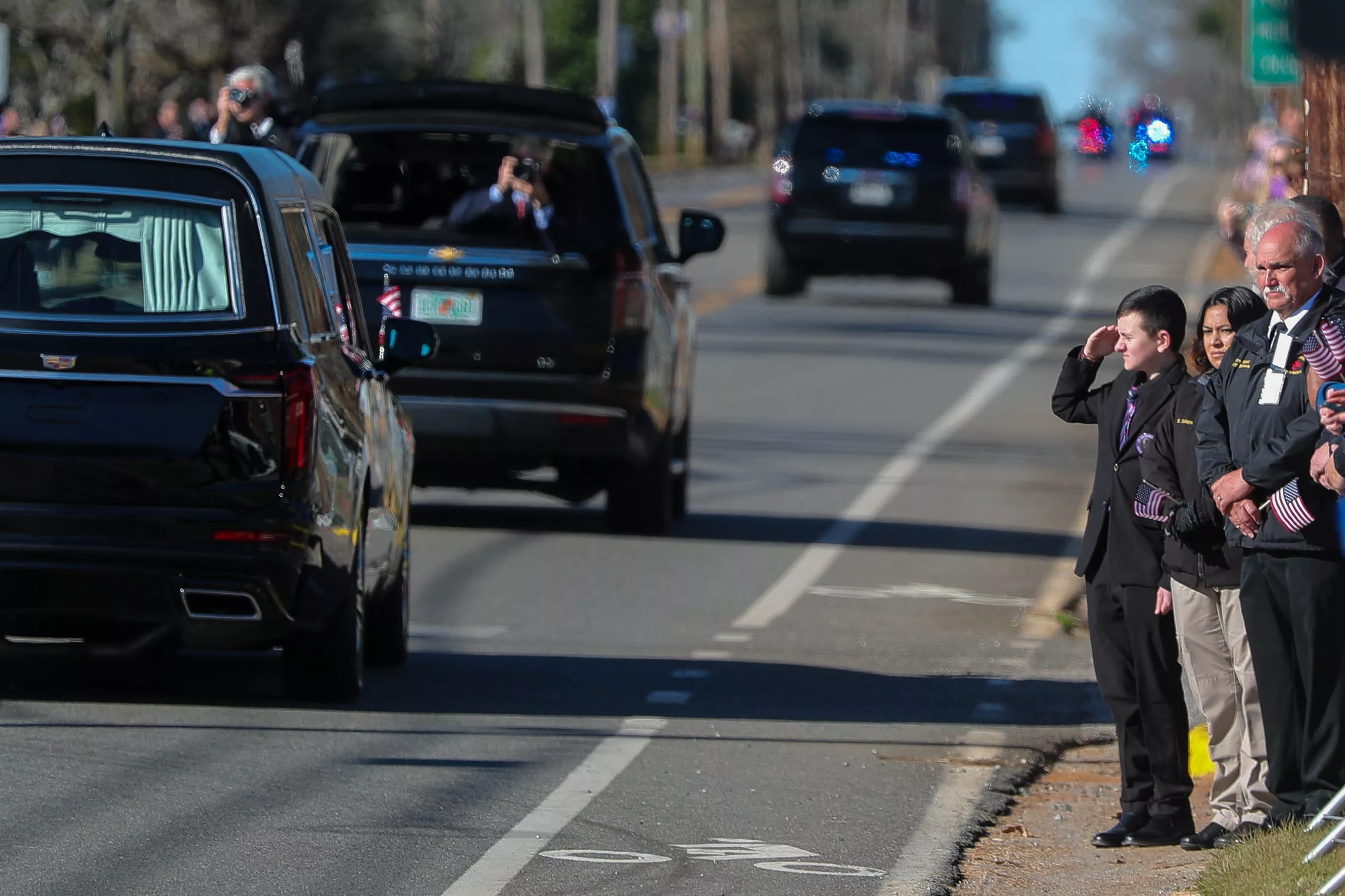 A boy in a formal suit salutes as the hearse carrying former President Jimmy Carter travels along the through Plains, Georgia on Saturday, Jan. 4, 2025.