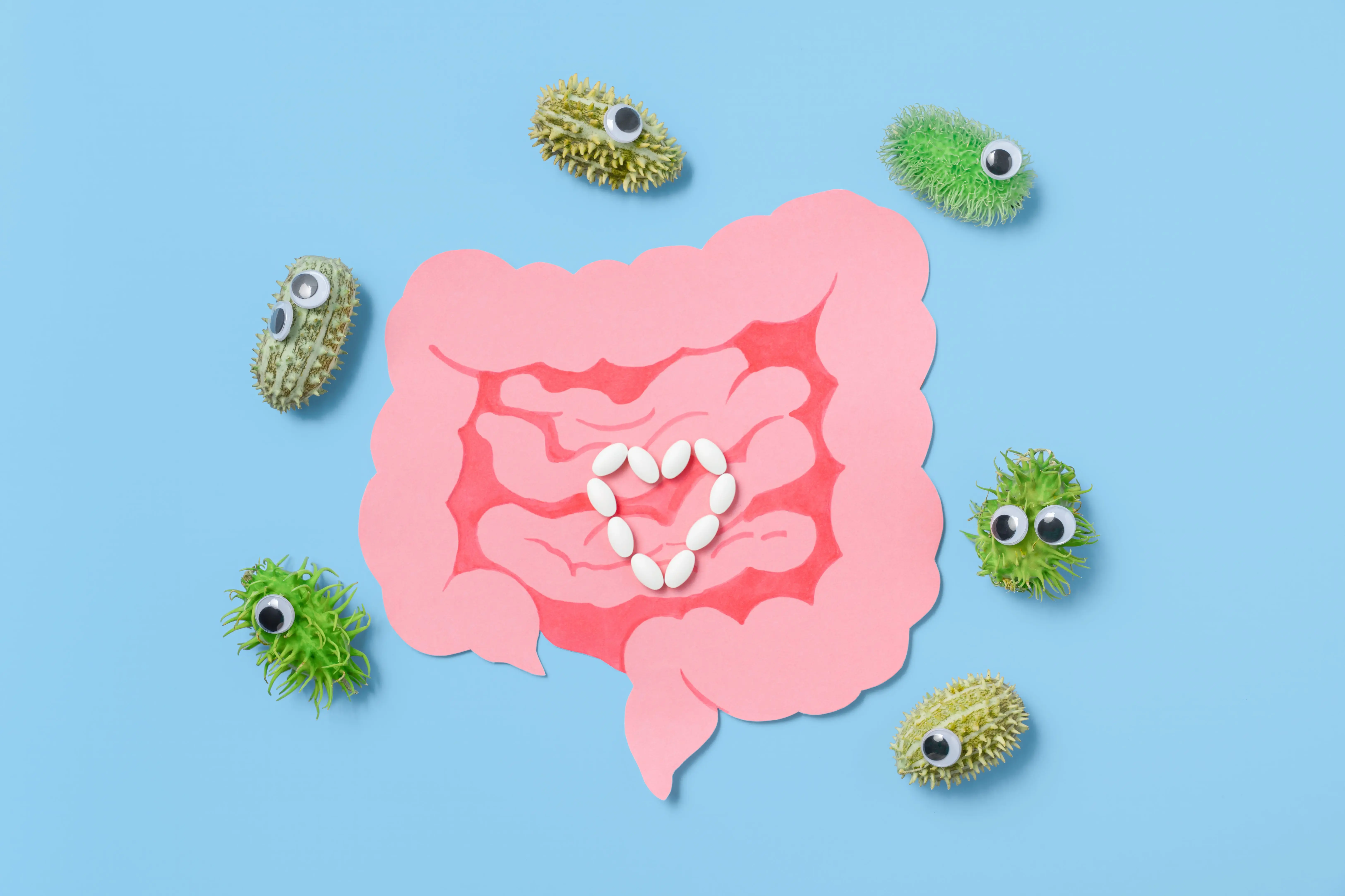 paper-gut-with-pills-and-funny-bacteria-on-blue-background