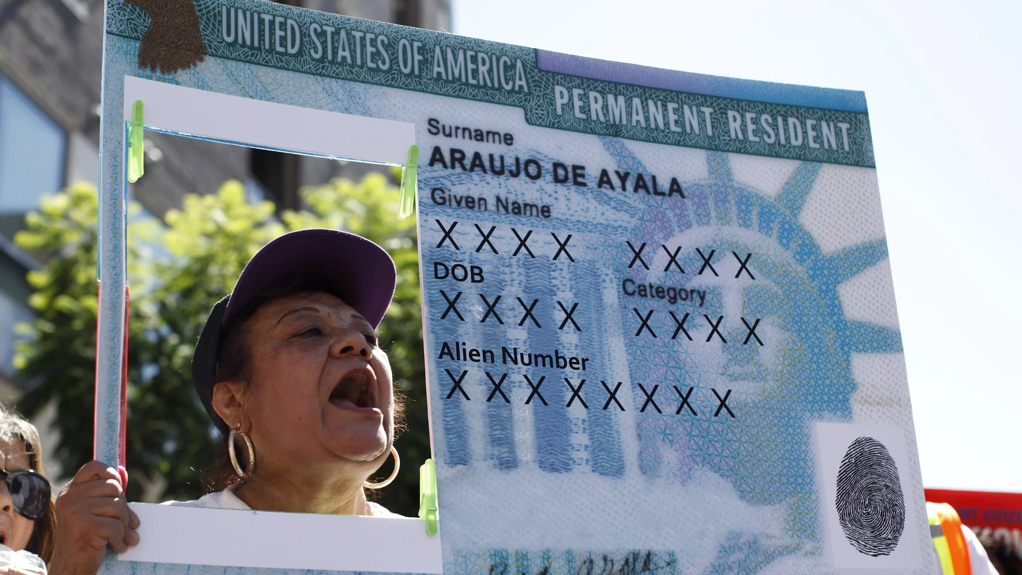 a-woman-holds-a-replica-green-card-sign-during-a-protest-march-to-demand-immigration-reform-in-hollywood
