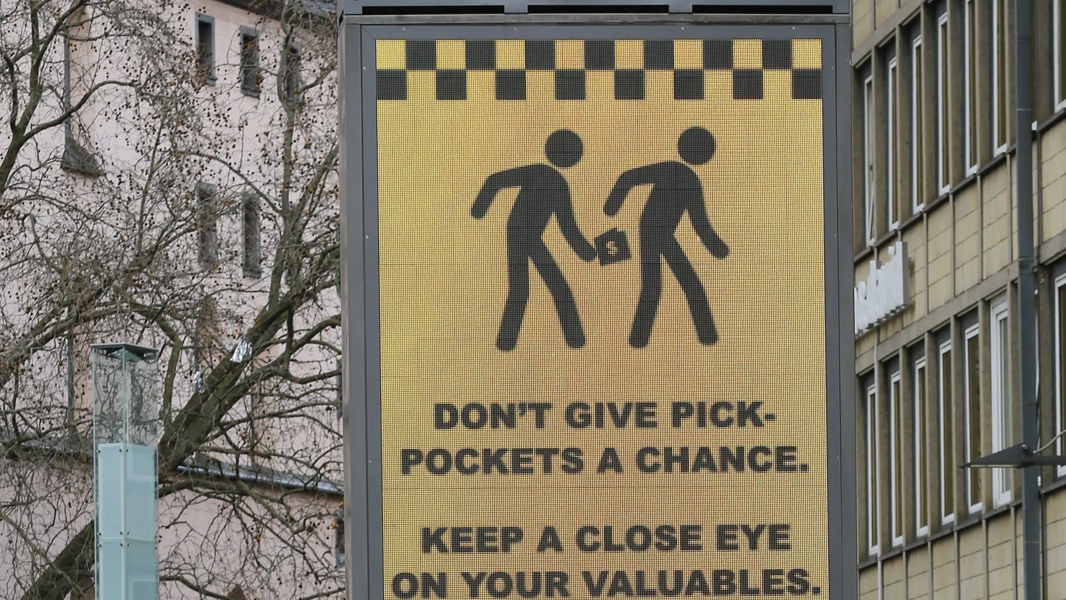pedestrians-walk-past-an-electronic-information-sign-warning-the-general-public-against-pickpockets-in-cologne