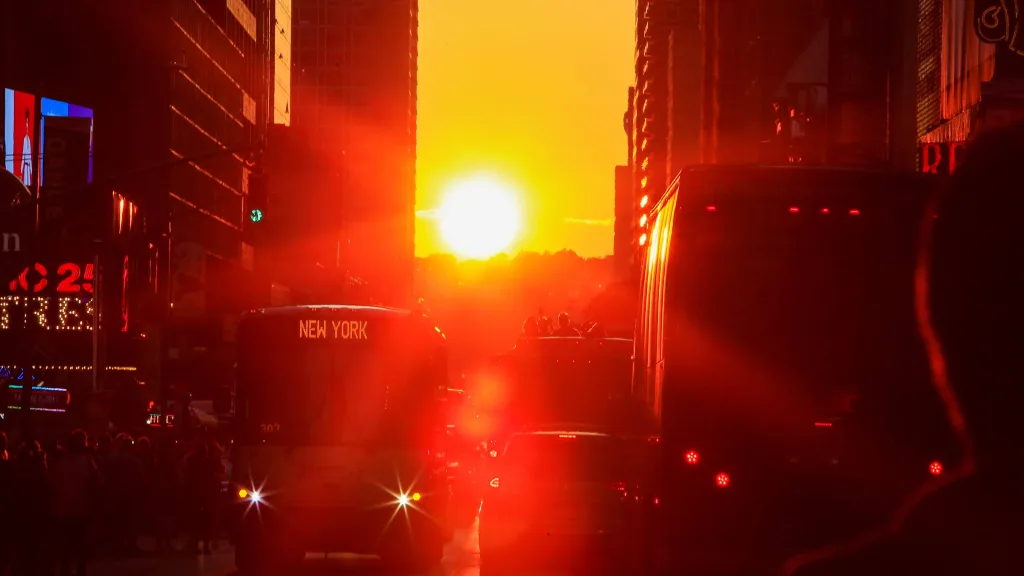 people-watch-the-sun-sets-over-manhattan-aligned-exactly-with-the-streets-in-a-phenomenon-known-as-manhattanhenge-in-times-square-in-new-york