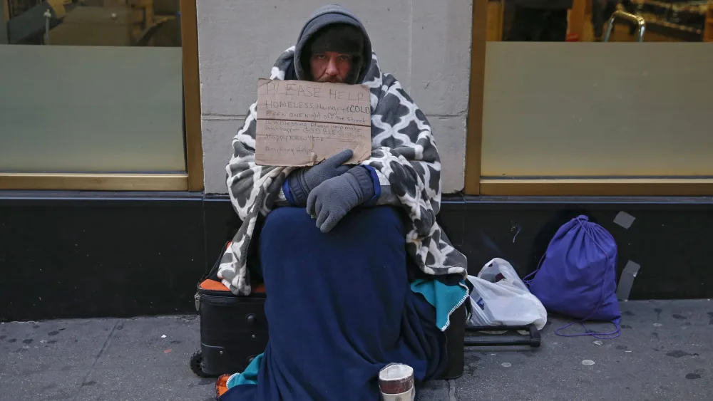 a-man-holding-up-a-sign-stating-he-is-homeless-hungry-and-cold-sits-along-7th-avenue-in-new-york