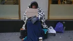 a-man-holding-up-a-sign-stating-he-is-homeless-hungry-and-cold-sits-along-7th-avenue-in-new-york