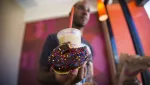 patron-nick-grace-holds-a-chocolate-glazed-donut-and-a-coffee-drink-at-a-newly-opened-dunkin-donuts-store-in-santa-monica