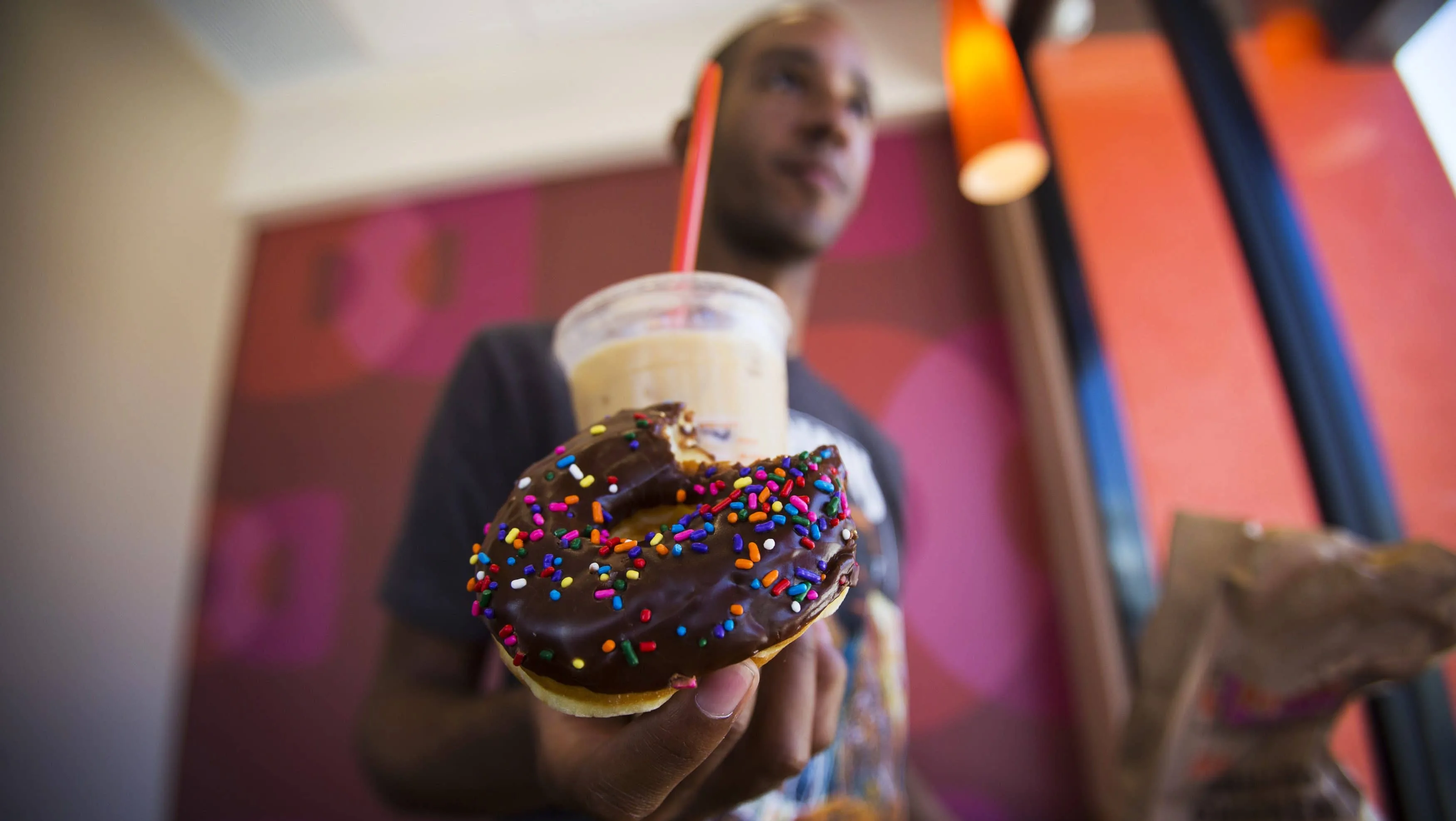 patron-nick-grace-holds-a-chocolate-glazed-donut-and-a-coffee-drink-at-a-newly-opened-dunkin-donuts-store-in-santa-monica
