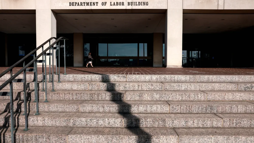 a-woman-walks-into-the-u-s-department-of-labor-which-published-its-weekly-initial-jobless-claims-report-in-washington