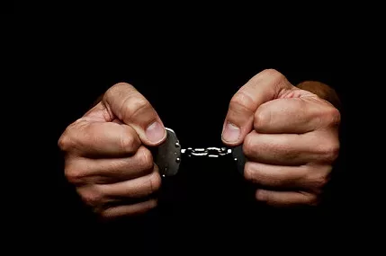 handcuffes-on-man-hands-on-black-background