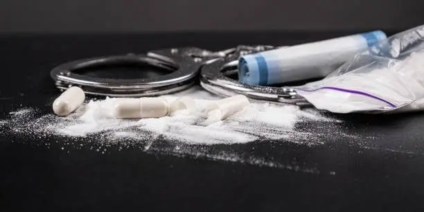 handcuffs-with-drugs-on-the-table-close-up-concept-of-law-and-drugs