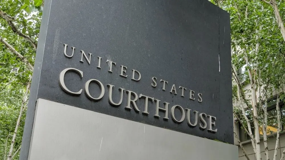The United States Courthouse sign stands tall amidst a serene backdrop of trees at the US District Court in Seattle^ Washington. Seattle - May 17^ 2019: