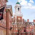 View of the architecture of the famous Harvard University in Cambridge^ Massachusetts^ USA showcasing it brick buildings with some students and locals passing by . Cambridge^ MA^ USA - March 15^ 2024