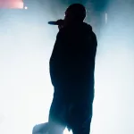 rapper on stage/shown from back under spotlight/in silhouette.