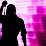 Silhouette of an artist singing live on the stage in the front of a colorful background