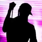 Silhouette of an artist singing live on the stage in the front of a colorful background