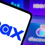 Photo illustration of the Max logo is seen displayed on a smartphone and the HBO Max and Discovery logo on the background
