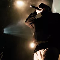 Rapper in hoody with microphone on the stage.