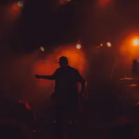 rap singer on stage/ cellphone lighting shown^ dark ambiance