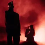 Silhouettes of two singers in the smoke. Red Illumination. Man sings on the stage.
