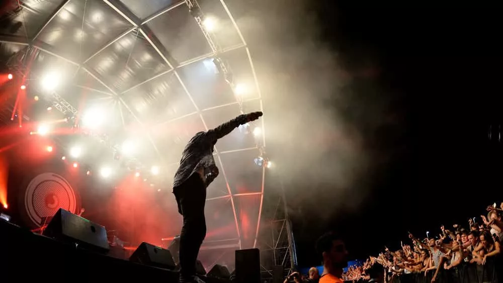 rapper/artists performing on stage^ holding mic to the crowd^ silhouette/lighting in white and red