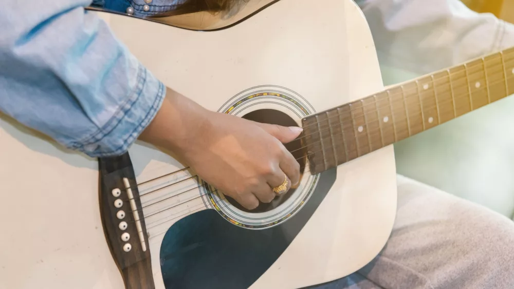 Close up woman's hands playing acoustic guitar.