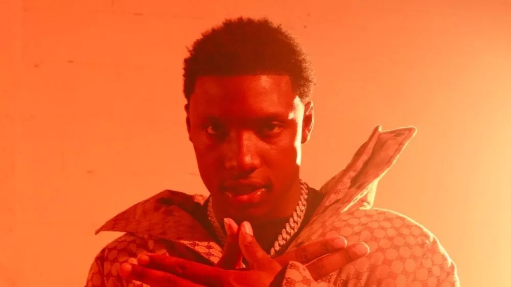 Rapper (Rob49) at an editorial shoot. Wearing diamond jewelry^ chains^ and rings. The rapper is dressed in a Gucci Down Coat and a black crewneck sweater.