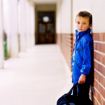 side-profile-of-a-young-boy-8-10-leaning-against-a-wall-in-school