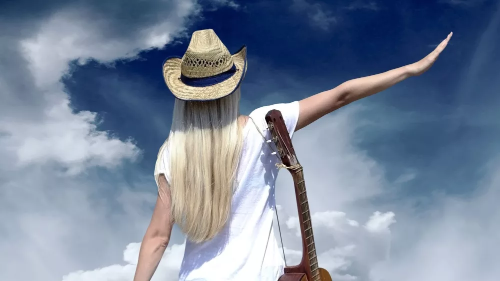 Young woman with guitar on the road and her vintage baggage