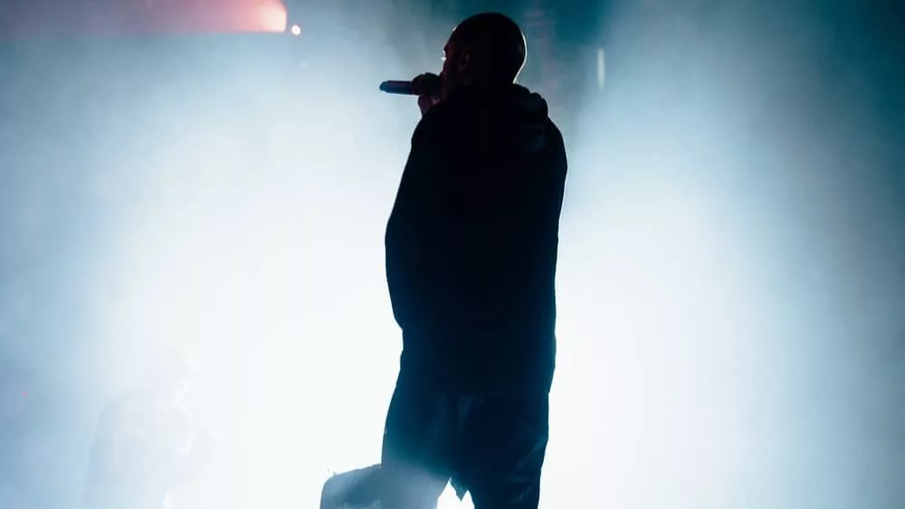 rapper on stage/shown from back under spotlight/in silhouette.