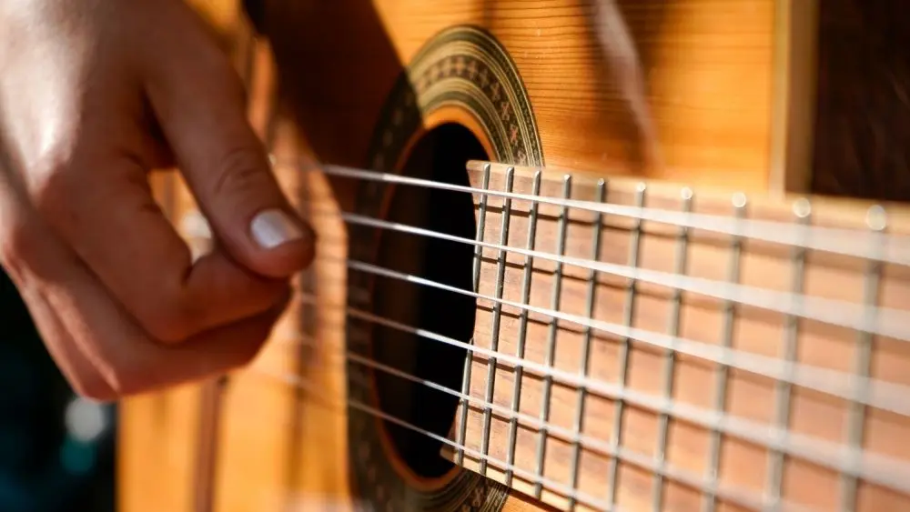 A woman plays an acoustic guitar.