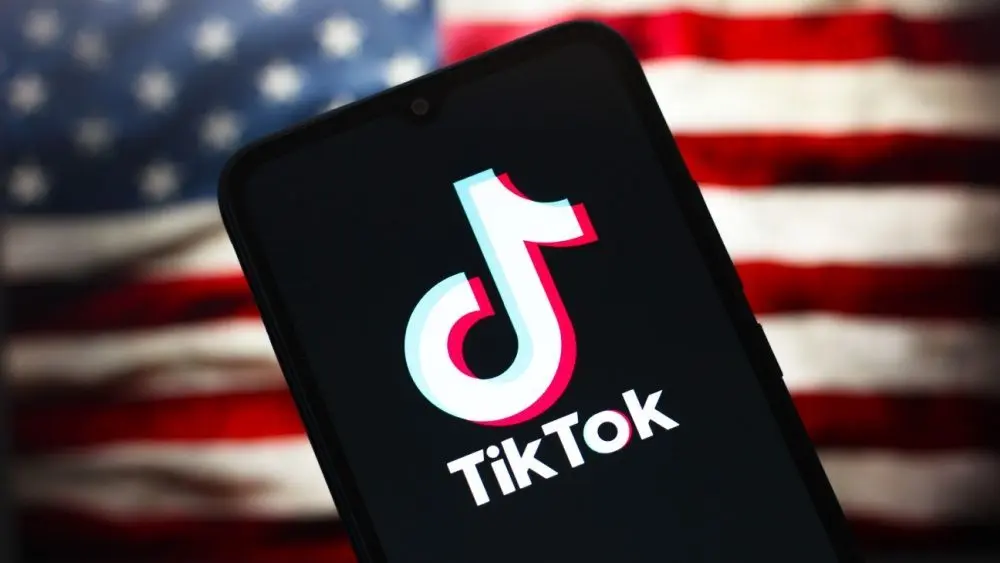 TikTok logo is seen displayed on a smartphone screen and in the background^ the United States flag^ in Reno^ United States^ on January 15^ 2025 In this photo illustration^ the TikTok logo is seen displayed on a smartphone screen and in the background^ the United States flag^ in Reno^ United States^ on January 15^ 2025