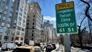 Cars driving down Fifth Avenue next to a "Toll: Congestion relief zone south of 61 Street" sign on the Upper East Side of Manhattan^ New York City New York^ NY USA - January 7^ 2025