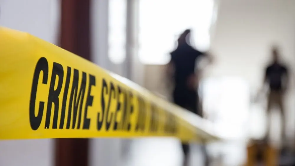 crime scene tape in building with blurred forensic team background