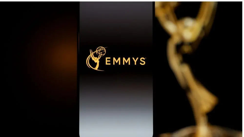 Emmys logo displayed on a smartphone screen with a blurred gold award statuette in the background^ television industry awards and digital streaming concept. Kaunas^ Lithuania - 2026 March 24