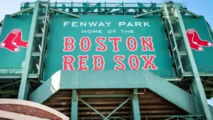 View of the historic architecture of the Fenway Park Stadium showcasing its signs^ brick walls^ statues^ and the famous green color and red letters of the red sox. Boston^ MA^ USA - March 10^ 2023