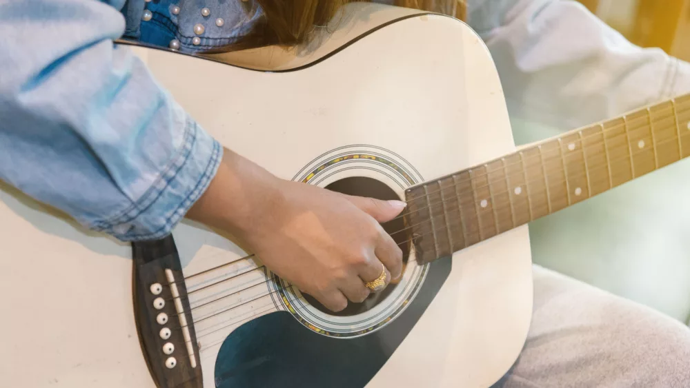 Close up woman's hands playing acoustic guitar.