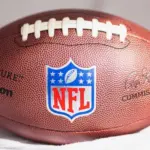 NFL Wilson Duke ball over a white sofa in a home. Sun light comes from a window.