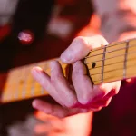 Close up look of hands of a man playing the electric guitar during a concert