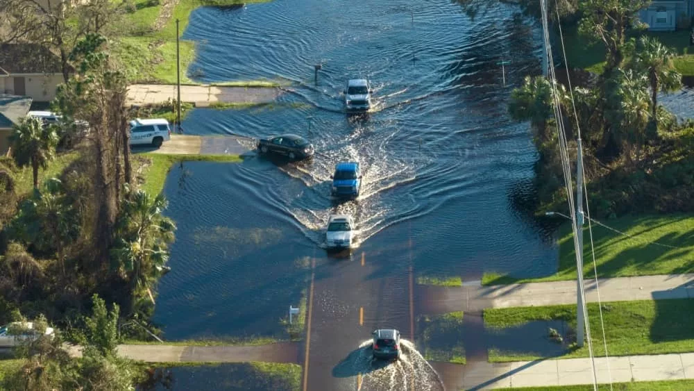 Flooded road in Florida after heavy hurricane rainfall. Aerial view of evacuating cars and surrounded with water houses in suburban residential area