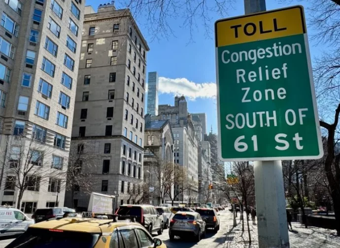 Cars driving down Fifth Avenue next to a "Toll: Congestion relief zone south of 61 Street" sign on the Upper East Side of Manhattan^ New York City New York^ NY USA - January 7^ 2025