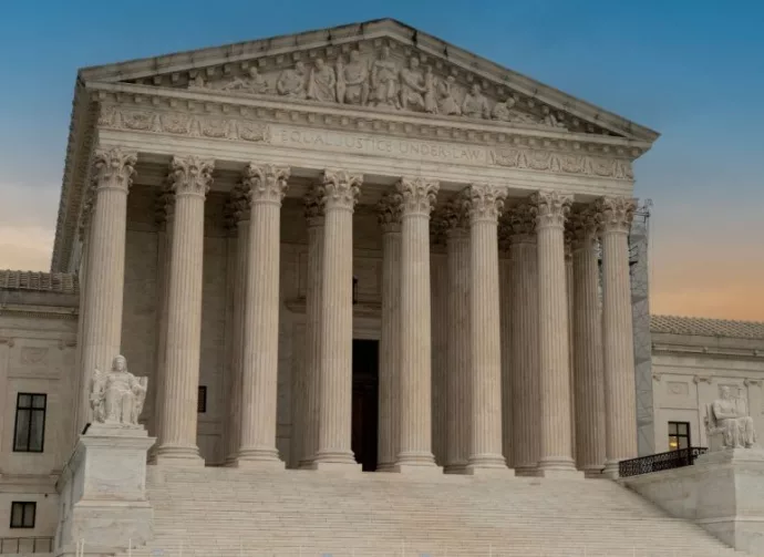 Greek classical architecture of the United States Supreme Court building with sunrise in background.