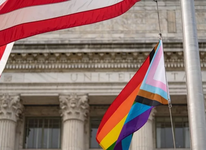 Waving Pride LGBT flag next to the flag of USA