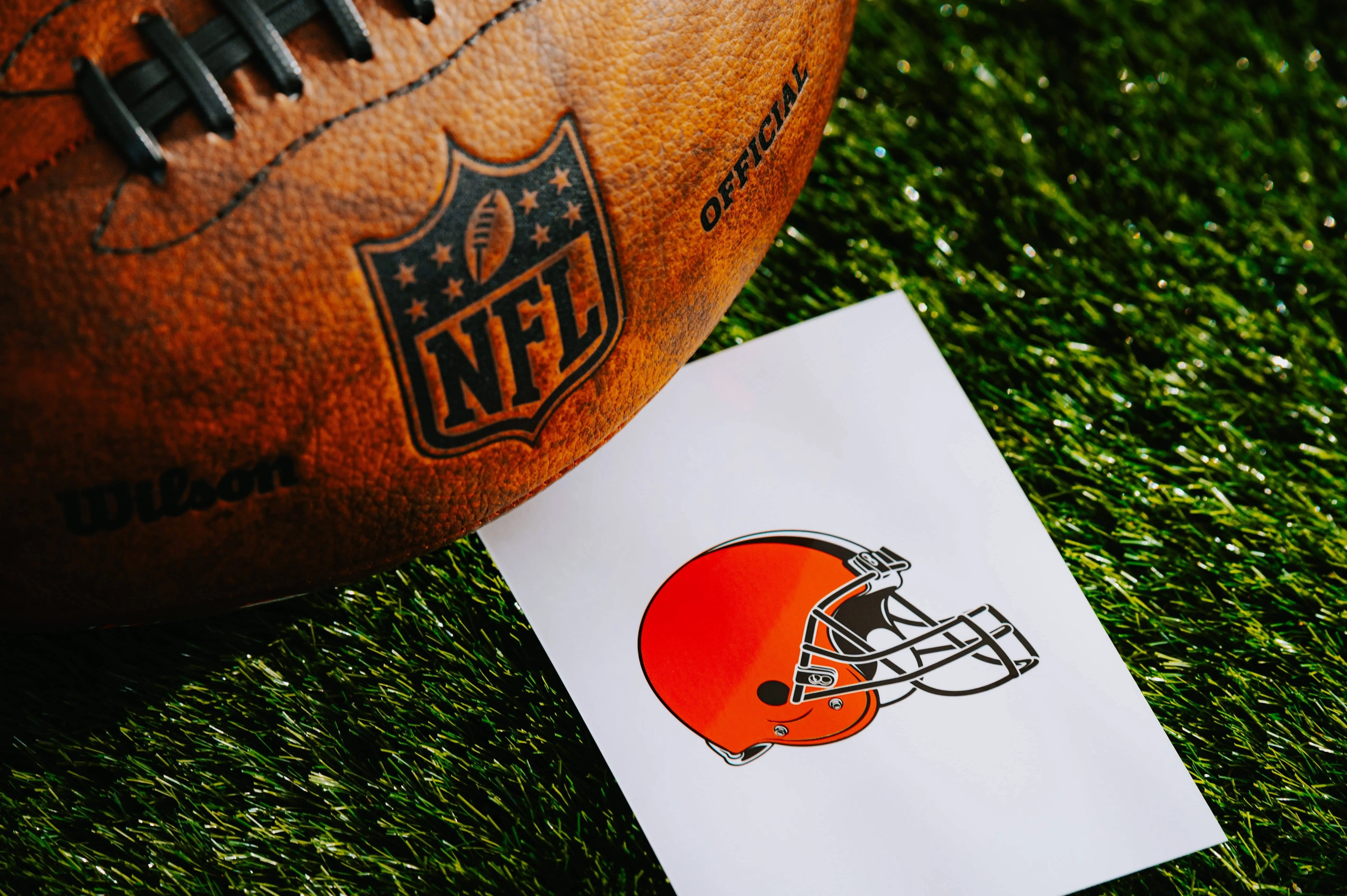 Cleveland Browns NFL team Logo and American football ball on Green Grass.