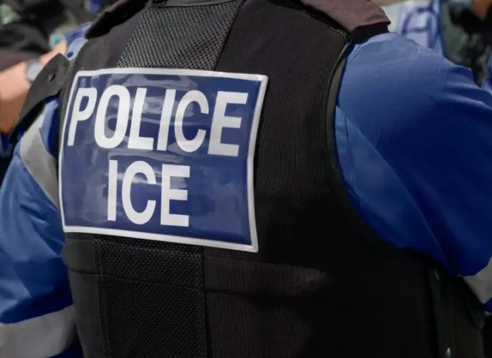 ICE police agent - Officer of Immigration and Customs Enforcement. Close-up of POLICE ICE marking on the back of a stab proof vest uniform worn by a trio of police officers at the scene of an incident