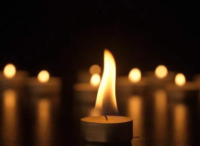 Burning candles. The candles burn against a black background and the flames move when the wind blows. The concept of a memorial day. Background for advertising and design projects.