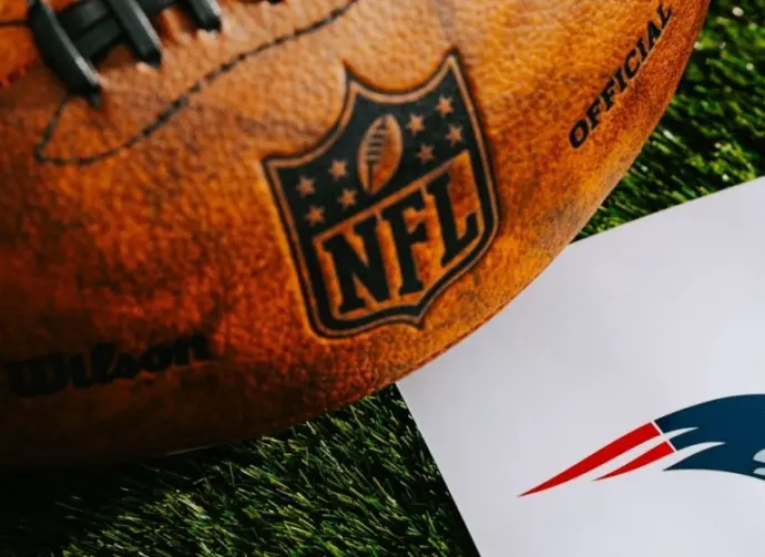 New England Patriots NFL team Logo and American football ball on Green Grass.