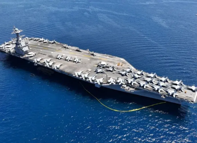 Aerial drone photo of USS Gerald R. Ford latest technology nuclear powered aircraft carrier anchored in deep blue open ocean sea